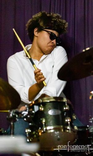 Tamara Williams with sunglasses playing the drums